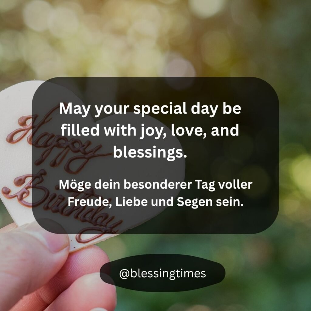 A hand holds a heart-shaped 'Happy Birthday' cookie with the English and German message: "May your special day be filled with joy, love, and blessings. Möge dein besonderer Tag voller Freude, Liebe und Segen sein."